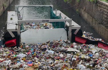 DESMI trash collector in a canal filled with debris and waste.