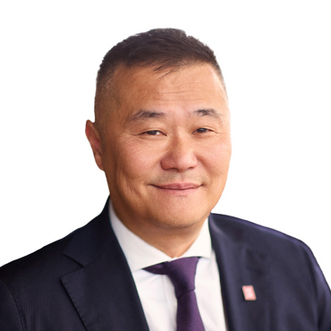 Man in a dark suit and white shirt on a plain background.