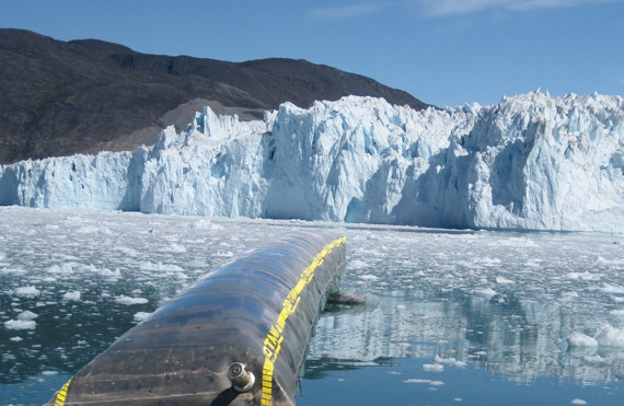 Floating DESMI oil boom in icy waters near a glacier.
