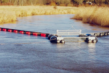 Floating barrier system in a river for controlling debris and water flow.