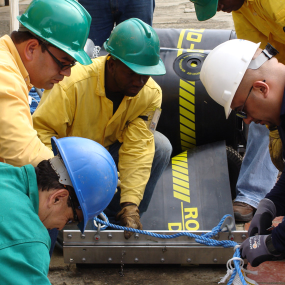 Workers in hard hats collaborate on equipment setup, focusing on a heavy-duty pump.