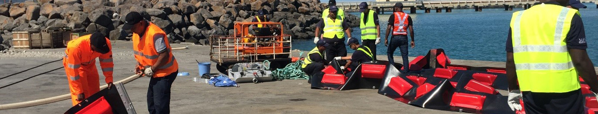 Workers in safety vests assembling equipment on a dock near water.
