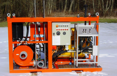 Orange DESMI hydraulic power unit on snow, featuring control panel and hoses.