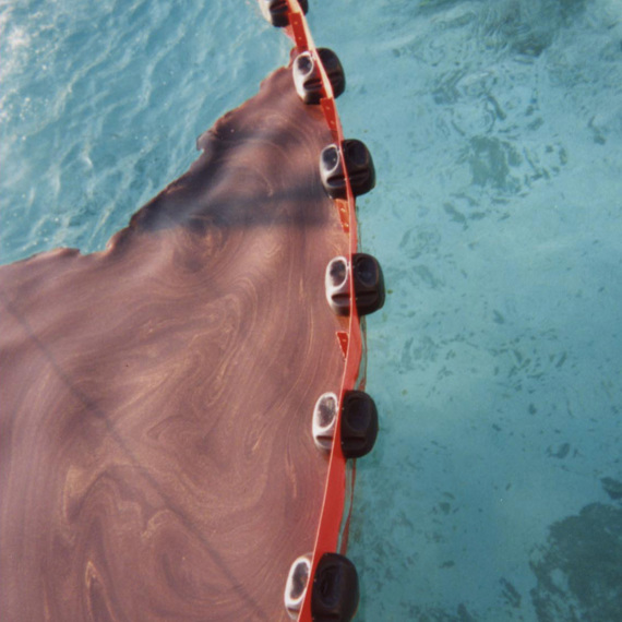 Oil spill containment boom floating on blue water surface.