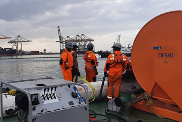DESMI oil spill response equipment in action with crew at a port.