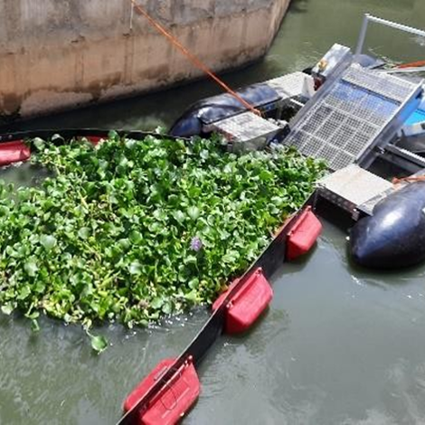 DESMI device collecting aquatic plants in a waterway for environmental management.