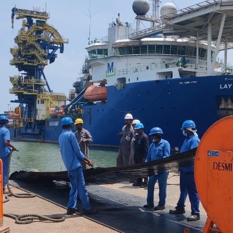 Workers handling equipment on dock near Lay Vessel 108 with DESMI machinery.
