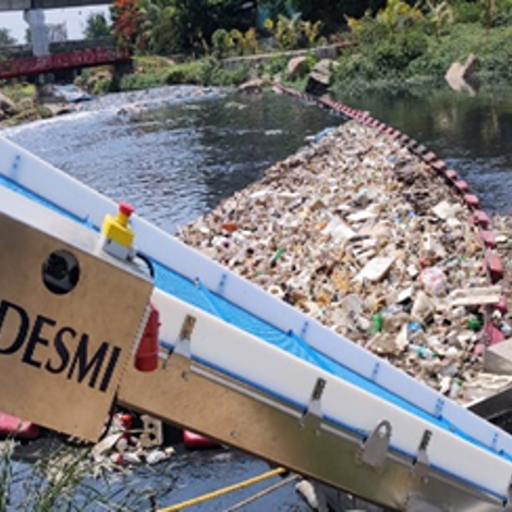 DESMI equipment collecting debris from a river for environmental cleanup.