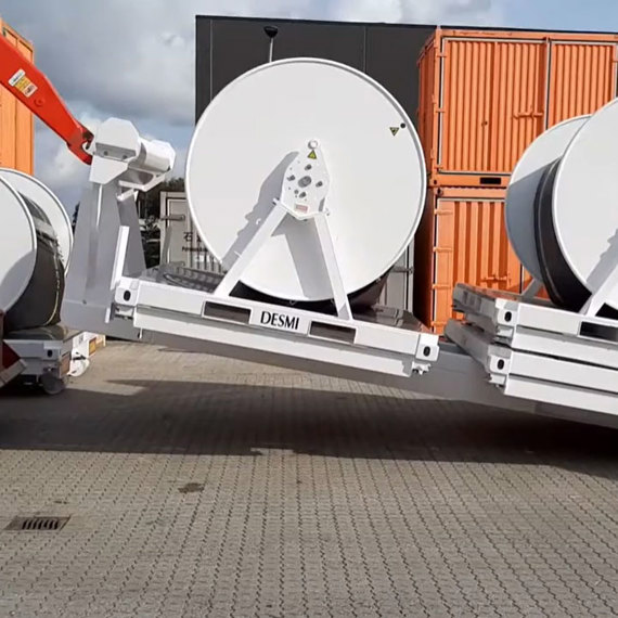 DESMI industrial hose reels on pallets, with orange containers in the background.