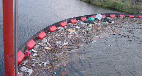 Floating barrier with collected debris and trash in a waterway.
