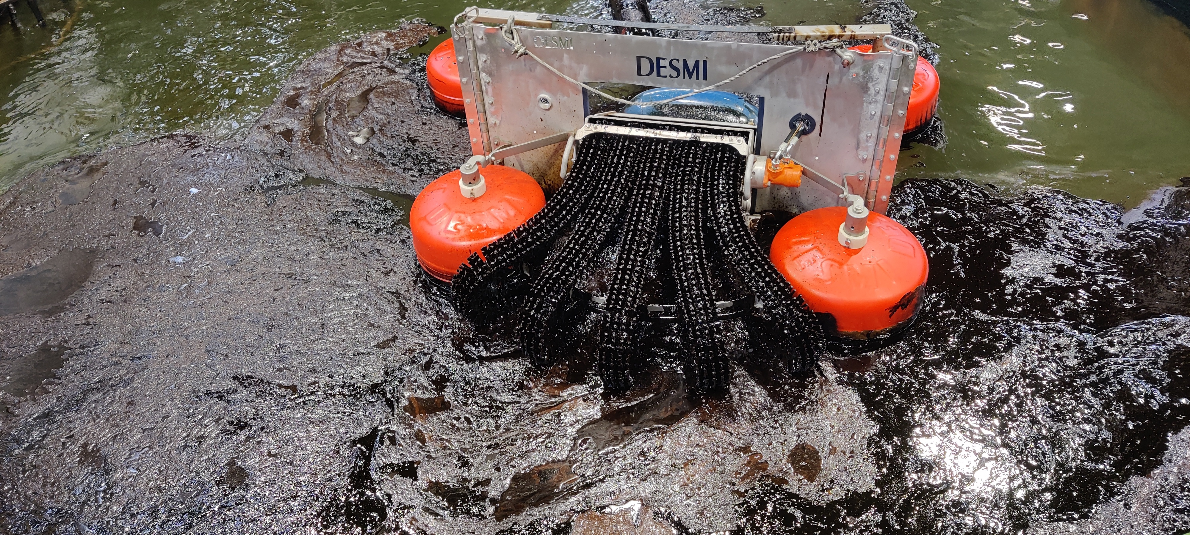 DESMI oil spill recovery skimmer operating in water with visible oil slick.