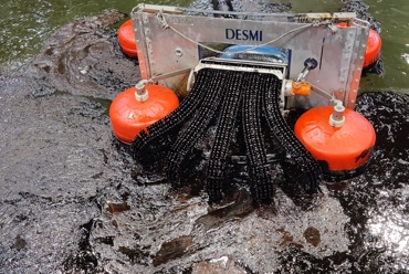 DESMI oil spill recovery skimmer operating in water with visible oil slick.