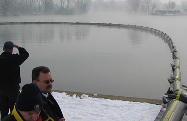 People observing a floating barrier on a misty lake in winter.