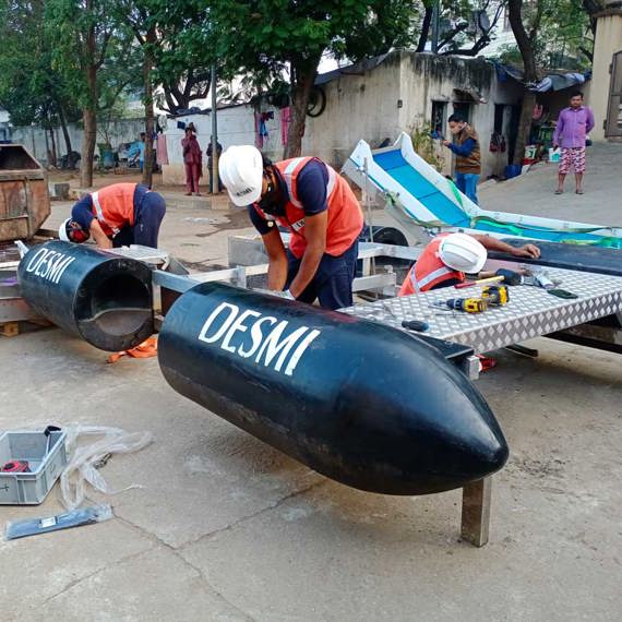 Workers assembling DESMI equipment for fluid handling outdoors.
